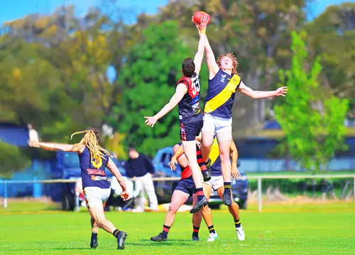 Footballers leap for the ball in a ruck contest